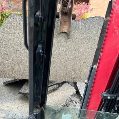 Excavator operator lifting concrete debris at a construction site.