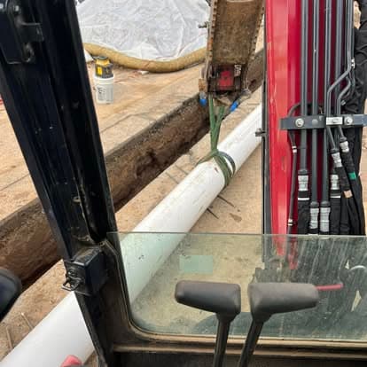 Interior view of an excavator with visible hydraulic controls and a construction site background.