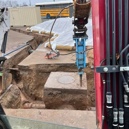 Construction site with excavated area, machinery, and exposed infrastructure.