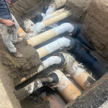 Excavation site showing multiple underground pipes in need of repair or maintenance.