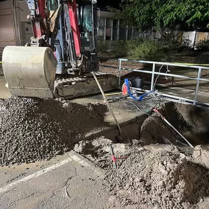 Excavator on gravel site with tools, part of a construction project at night.